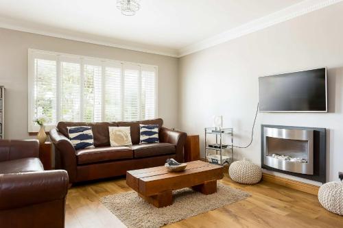 a living room with a couch and a tv at Sandy Shores - Moments from Blue Flag Sandbanks Beach in Poole
