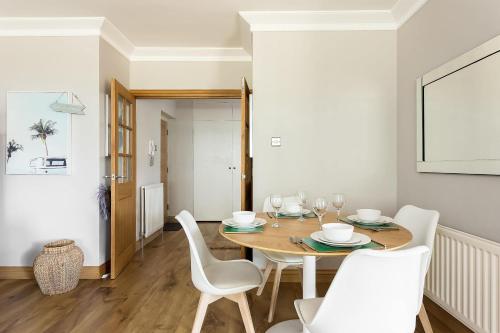 a dining room with a wooden table and white chairs at Sandy Shores - Moments from Blue Flag Sandbanks Beach in Poole