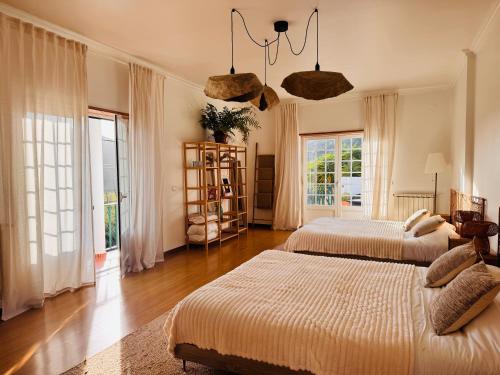 a bedroom with two beds and a large window at Casa Nabia - Coastal Sanctuary in Ericeira