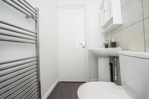 a white bathroom with a toilet and a sink at Modern 4 Bedroom House Sleeps 10 Free Parking Liverpool in Litherland
