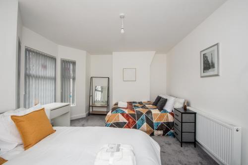 a white bedroom with two beds and a mirror at Modern 4 Bedroom House Sleeps 10 Free Parking Liverpool in Litherland