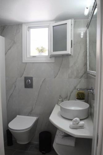 a bathroom with a toilet and a sink and a window at Enalios House in Vourvoúlos