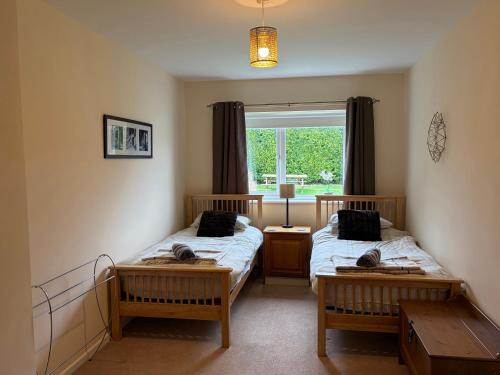two twin beds in a room with a window at Jacuma in Rhosneigr