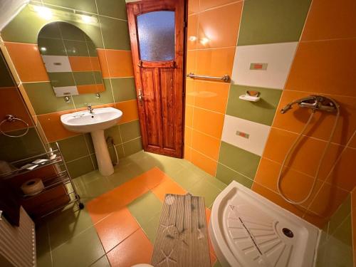an orange and green bathroom with a toilet and sink at Raza Soarelui in Moieciu de Sus