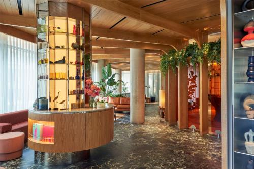 a lobby of a hotel with a bar and plants at The BoTree London, Curio Collection by Hilton in London