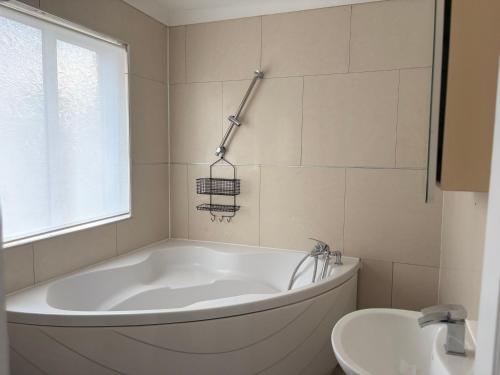 a white bath tub in a bathroom with a sink at Modern Guest Rooms Near Wembley Stadium- Free parking & WiFi in London