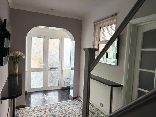 a hallway with a staircase with a door and windows at Modern Guest Rooms Near Wembley Stadium- Free parking & WiFi in London