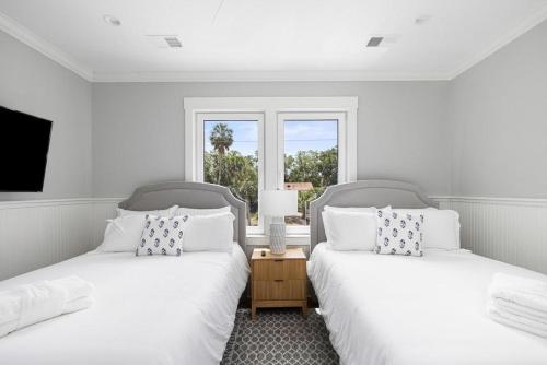 two beds in a white room with a window at Jungle House-Heated Pool-Pet Friendly-Luxury in Edisto Island