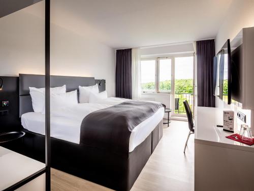 ein Hotelzimmer mit einem großen Bett und einem Schreibtisch in der Unterkunft DORMERO Hotel Weimar in Weimar