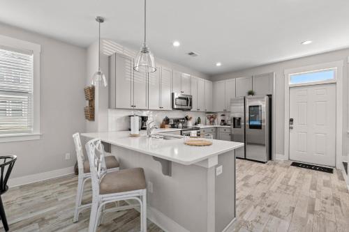 a kitchen with white cabinets and a kitchen island with chairs at Creekside Bungalow-Park Circle-15m dtwn CHS in Charleston