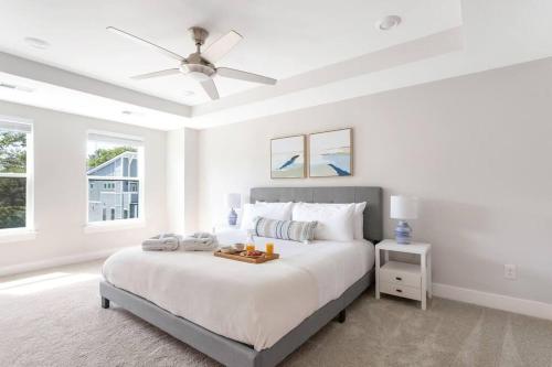 a white bedroom with a bed with a ceiling fan at The Trendy In Park Circle Mins to DT CHS & Beach in Charleston