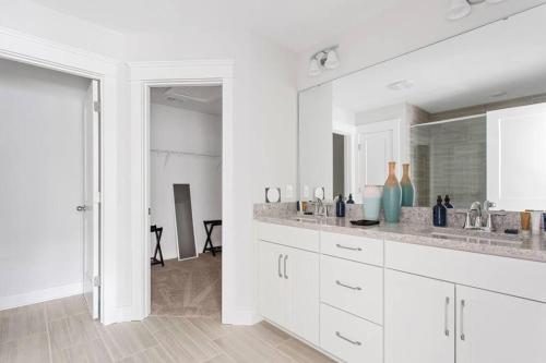 a white kitchen with a sink and a mirror at The Trendy In Park Circle Mins to DT CHS & Beach in Charleston