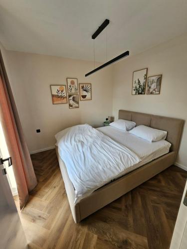 a bedroom with a large bed with white sheets at Loft Apartment in Podgorica