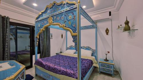 a bedroom with a blue and gold canopy bed at L Andalousie in Tabarka
