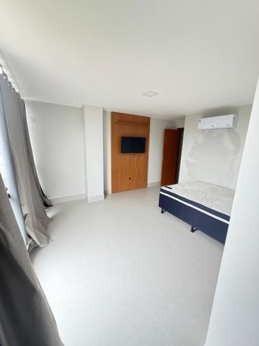 an empty room with a bed and a television at Recanto da Praia in Anchieta