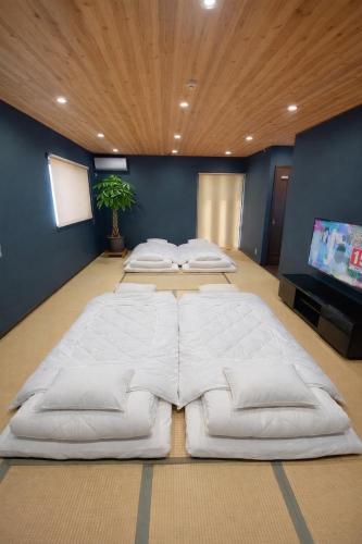 a large white bed in a room with a flat screen tv at 天然温泉付別荘Green House in Shirahama