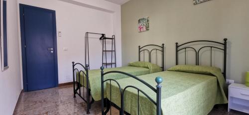 a bedroom with two beds and a blue door at Casa Vacanze Samelia in Altavilla Milicia