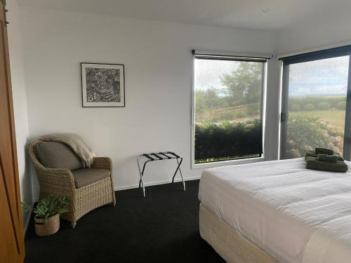 a bedroom with a bed and a chair and a window at Brooklyn Views - 4 Bedrooms in Feilding
