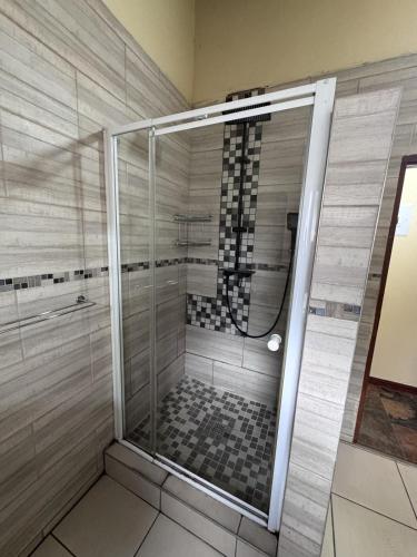 a shower with a glass door in a bathroom at Countryview Chalet in Benoni