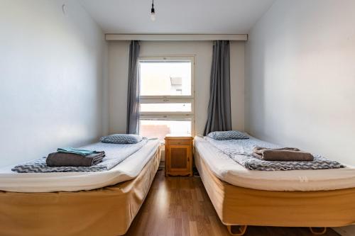 two twin beds in a room with a window at Kalastajankuja Apartment in Espoo