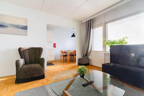 a living room with a television and a chair and a table at Kalastajankuja Apartment in Espoo