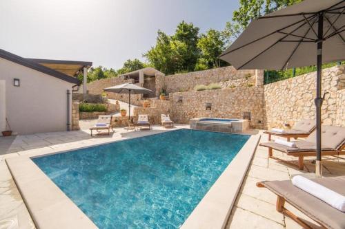 a swimming pool with chairs and an umbrella at Villa Argenta in Aržano