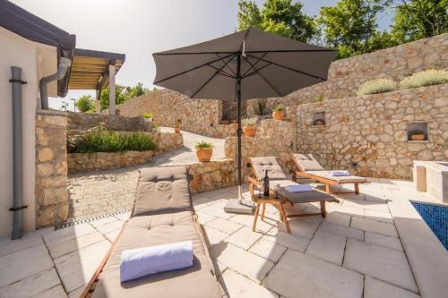 a patio with an umbrella and chairs and a pool at Villa Argenta in Aržano