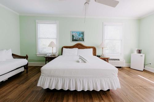 a bedroom with a white bed and two windows at King Suite at Curry Mansion with Heated Pool! in Key West