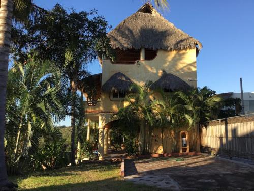 a large house with a thatched roof and palm trees at Beautiful Tropical House with Ocean VIEWS! in Cruz de Huanacaxtle