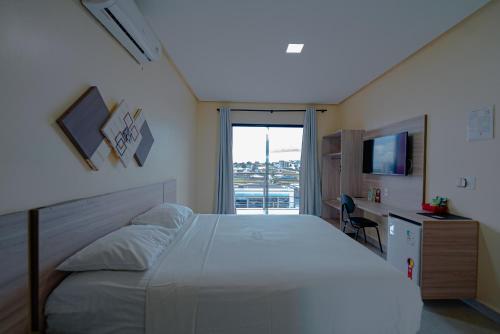 a bedroom with a bed and a desk and a television at Hotel Vale da Serra in Parauapebas