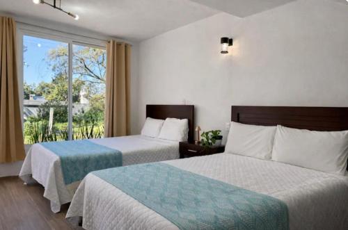 a hotel room with two beds and a window at Hotel El Balcón in Zacatlán