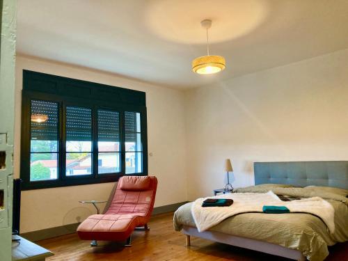 a bedroom with a bed and a pink chair at VILLA CLEMENTINE in Aignan