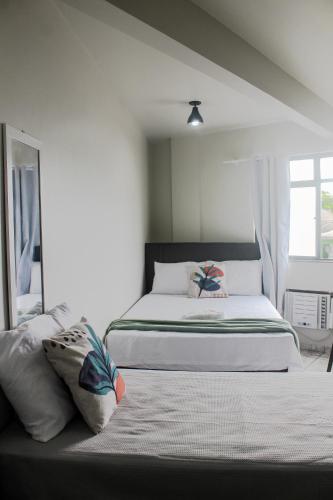 a white bedroom with two beds and a window at Loft Recanto Dos Cavalheiros! Com Ar Condicionado! in Macaé