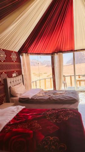 a bedroom with two beds and a large window at Joy to Wadi Rum in Wadi Rum