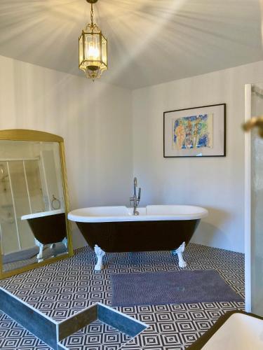 a bathroom with a large tub and a mirror at VILLA CLEMENTINE in Aignan