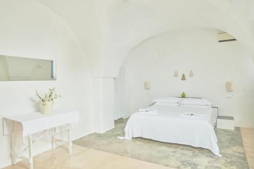 a white room with two beds and a table at Masseria Mozzone in Fasano