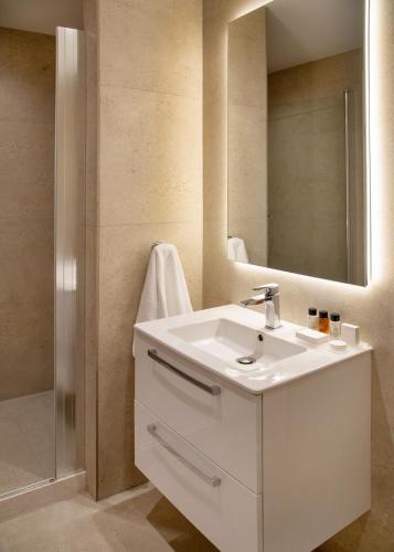 a bathroom with a white sink and a mirror at L Residences & Suites in Larnaca