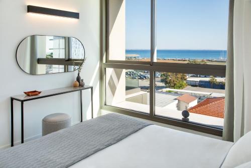 a bedroom with a bed and a large window at L Residences & Suites in Larnaca