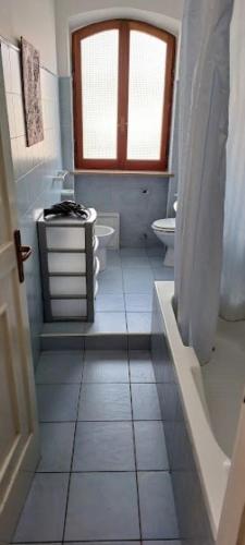 a white bathroom with a toilet and a window at Perla del Mare in Sperlonga