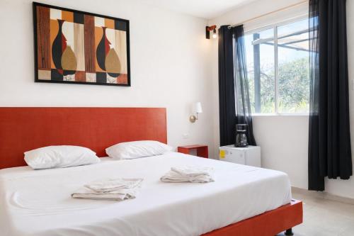 a bedroom with a bed with white sheets and a window at Guest house La Casa del Quetzal in Mérida