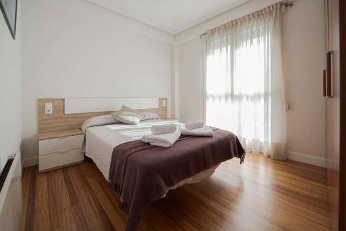 a bedroom with a bed with two towels on it at Bañeru Zarautz Centro - Sol, playa y confort, todo a un paso in Zarautz