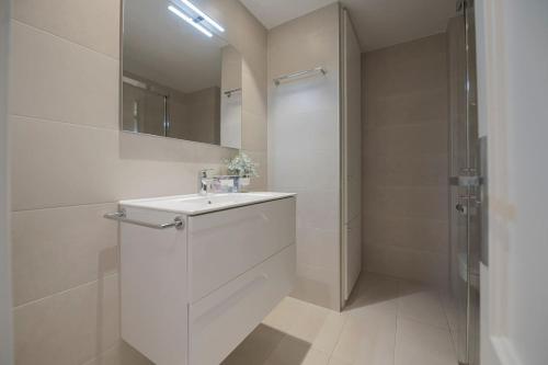 a white bathroom with a sink and a shower at Bañeru Zarautz Centro - Sol, playa y confort, todo a un paso in Zarautz
