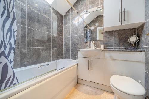 a bathroom with a toilet and a tub and a sink at The Retreat with Free Parking in Ambleside
