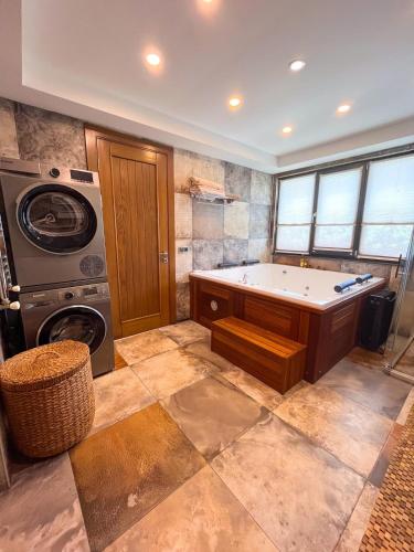 a bathroom with a tub and a washing machine at Villa Meg with Private Pool, Sauna Jacuzzi in Kadıköy