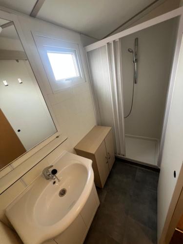 a white bathroom with a sink and a shower at Les mobil homes de NOLY TV CLIM 6places 1 place adulte offerte pour la réserve africaine sigean in Port-la-Nouvelle