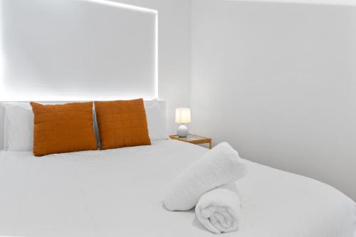 a white bedroom with a white bed with orange pillows at Georgies Simple Base in Mosman Park in Mosman Park