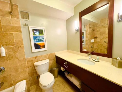 a bathroom with a toilet and a sink and a mirror at Pristine Hotel Room at Popular Resort in Lihue