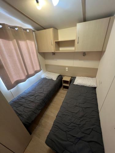 a small room with two beds and cabinets at Les mobil homes de NOLY TV CLIM 6places 1 place adulte offerte pour la réserve africaine sigean in Port-la-Nouvelle