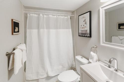 a white bathroom with a shower curtain and a toilet at USS Maddox in Libertyville