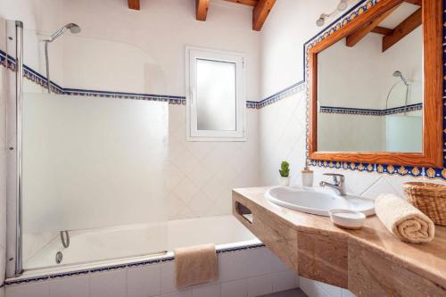 a bathroom with a sink and a tub and a mirror at Villa Maru III by Villa Plus in Cala en Porter